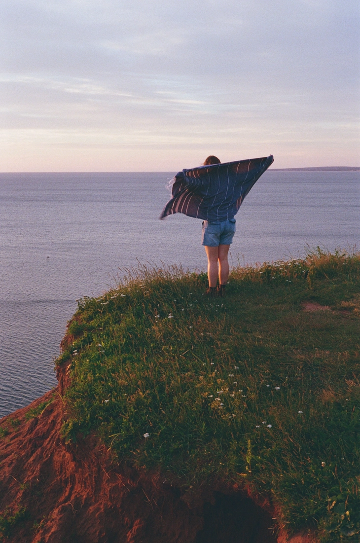 A picture of a girl standing on a cliff